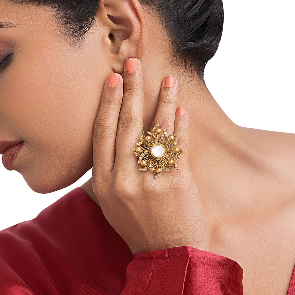 Traditional gold cocktail ring featuring an intricate floral design with a central white gemstone and detailed gold bead accents.