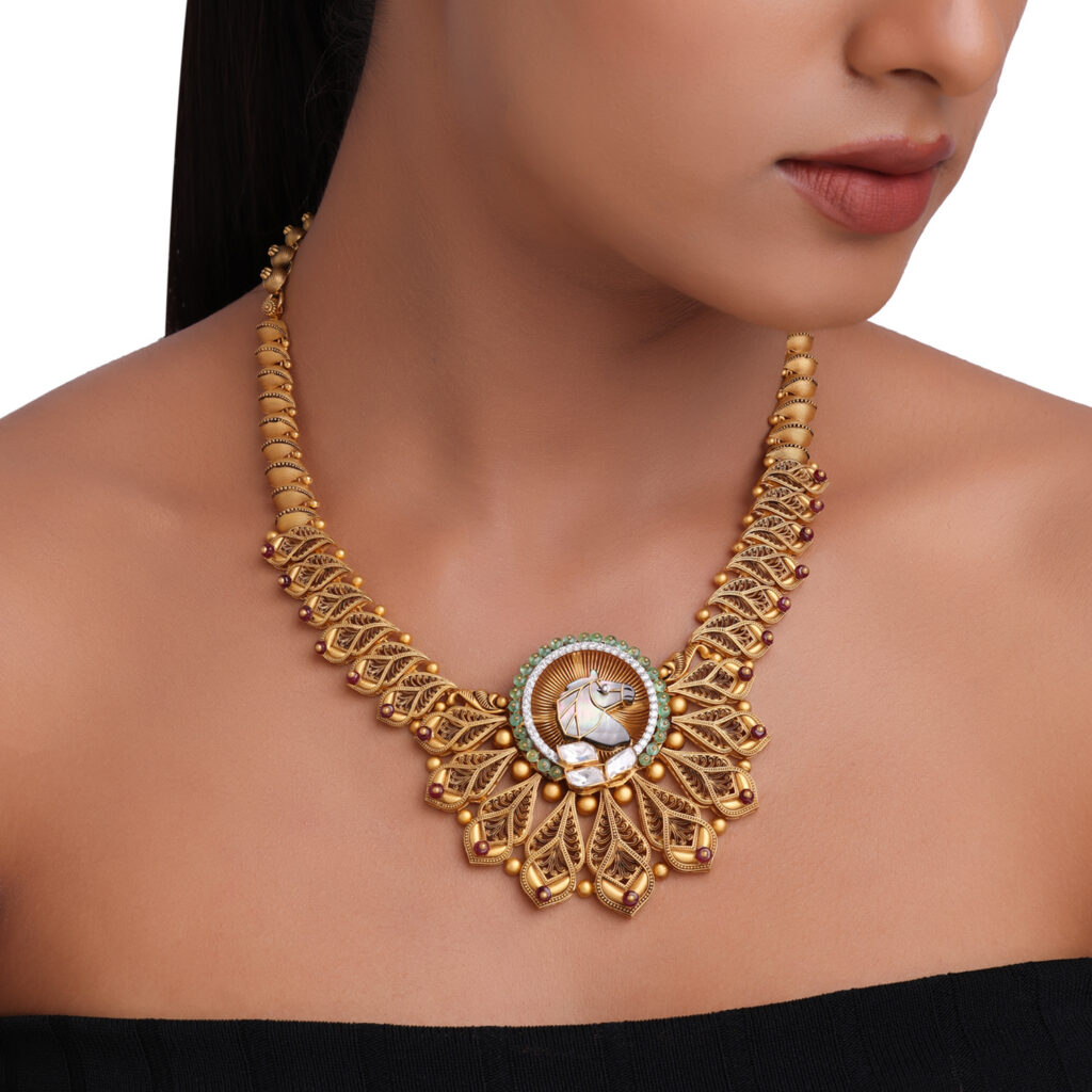Traditional gold necklace featuring an intricate filigree design with a horse motif centrepiece, coloured gemstones and detailed heritage-inspired craftsmanship.